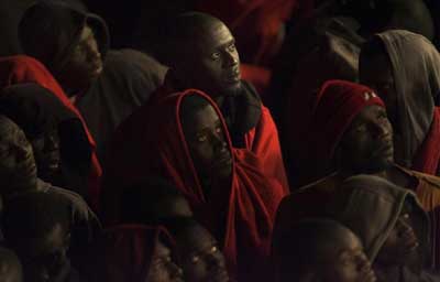 Migrants rest wrapped in blankets after arriving at Los Cristianos port on Spain's Canary Island of Tenerife early September 30, 2008. Some 229 would-be immigrants were rescued by Spanish rescue workers after being intercepted aboard a fishing boat adrift some 60 miles (96.5 km) offshore on their way to European soil from Africa, according to authorities. (REUTERS/Santiago Ferrero) 